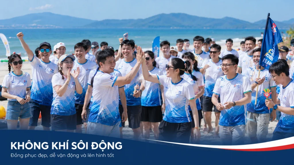 Ảnh team building bãi biển với đồng phục xanh trắng đồng bộ, thể hiện không khí sôi động, dễ vận động và lên hình đẹp trong chương trình doanh nghiệp.