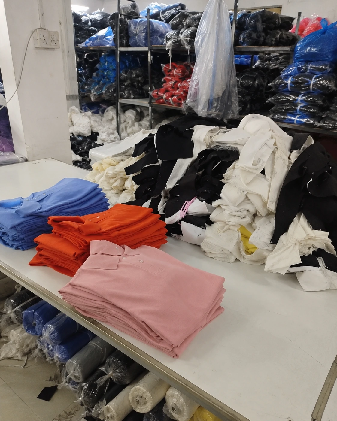 Áo polo phôi được gấp xếp trên bàn sản xuất trong xưởng may đồng phục